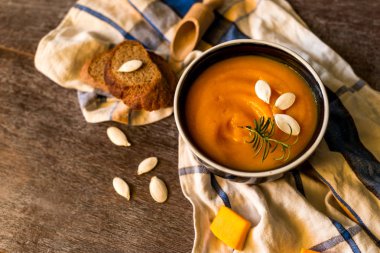 Kırsal ahşap bir masada sağlıklı kremalı balkabağı çorbası. Sonbahar balkabağı kremalı çorba biberiye ve kızarmış ekmek. Boşluğu kopyala