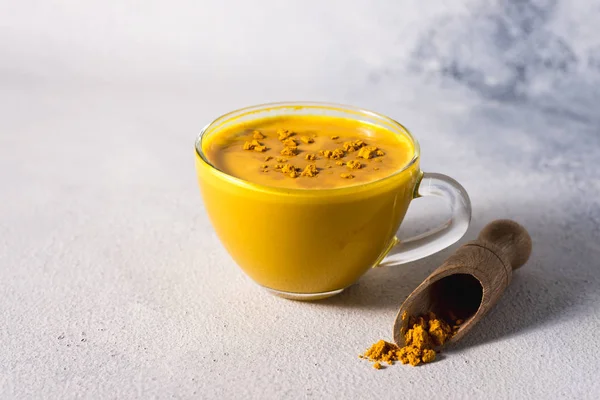 Beyaz zemin üzerinde altın zerdeçal sütü ve baharatlı tarçın ve malzemeler.