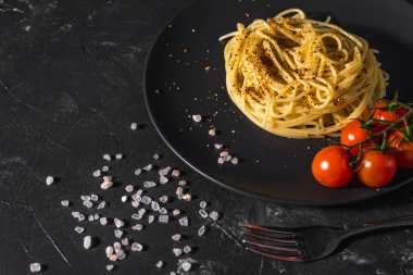 Domates soslu, peynirli ve koyu arkaplanda servis edilen sağlıklı baharatlı İtalyan spagettisi..
