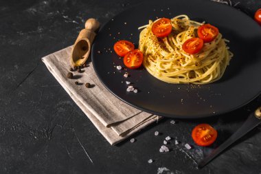 Domates soslu, peynirli ve koyu arkaplanda servis edilen sağlıklı baharatlı İtalyan spagettisi..