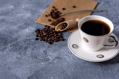 Kahve fincanı ve kahve çekirdekleri gri arka planda, mesajınız için yer var.