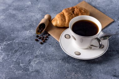 Kahve fincanı ve kahve çekirdekleri gri arka planda, mesajınız için yer var.