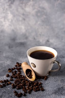 Kahve fincanı ve kahve çekirdekleri gri arka planda, mesajınız için yer var.