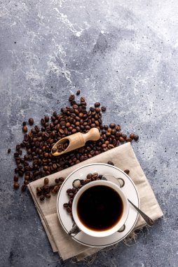Kahve fincanı ve kahve çekirdekleri gri arka planda, mesajınız için yer var.
