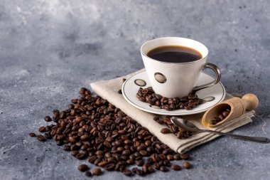 Kahve fincanı ve kahve çekirdekleri gri arka planda, mesajınız için yer var.