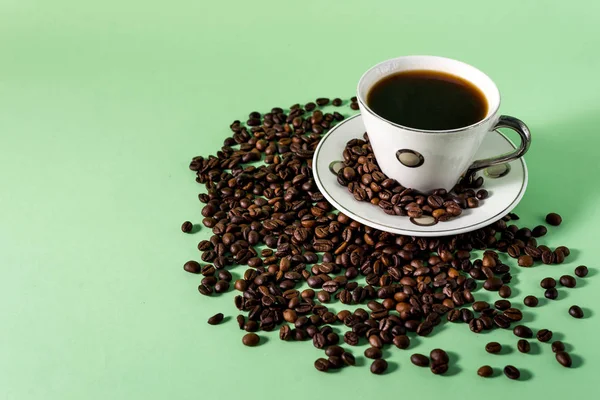 Coffee cup and coffee beans on a light mint background
