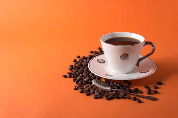 cup of aromatic coffee and coffee beans on an orange trendy background with space for text