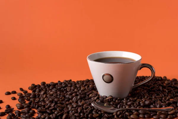 cup of aromatic coffee and coffee beans on an orange trendy background with space for text