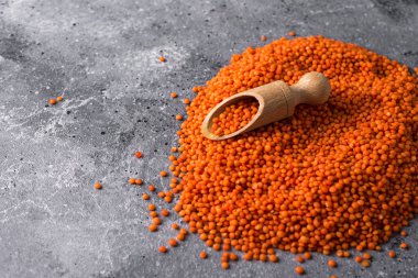 Gri arka planda mercimek ahşap kaşıkta kırmızı mercimek ve yakın plan sağlıklı yiyecek.