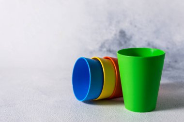 Gri taş arkaplan plastik atık üzerinde grup renkli plastik bardaklar