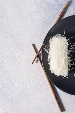 Siyah tabakta yemek çubukları olan Çin yapımı cam erişteler.