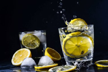 Limon dilimli cin ve tonik kokteyli. Limonlu buz küpü suya düşer. Kopya alanı, limonata.