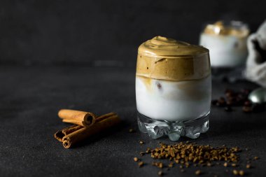 Dalgona kahvesi şeffaf bir fincanda, koyu bir arka planda. Kremalı kahve, şeker ve sütlü Güney Kore içeceği..