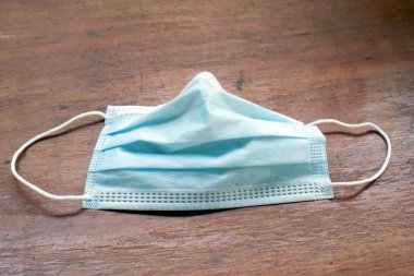 Tek kullanımlık yüz maskesi ağız ve burnu kapatır. Tahtada.