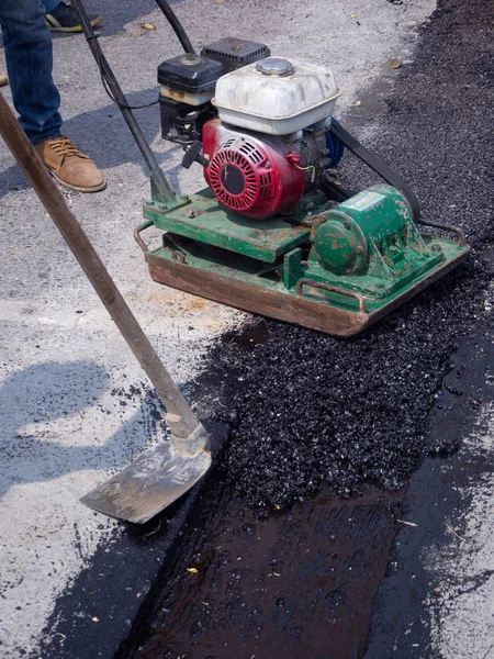 Il lavoratore usa il compattatore a piastre vibranti che compatta l'asfalto su strada — Foto Stock