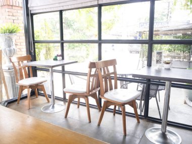 Tuğla kafeli ve barlı bir kafe, cam pencerelerin yanında sıra sıra sandalyeler.