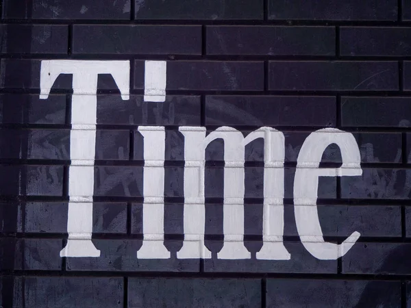 Black Brick Wall with Word Time in Worn White Paint