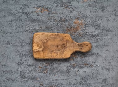 Gri beton arka planda tahta kesme tahtası. Tablo üstü görünümü