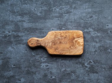 Gri beton arka planda tahta kesme tahtası. Tablo üstü görünümü