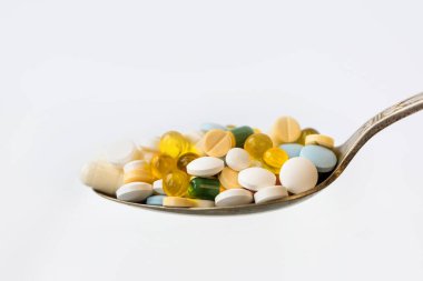 Beyaz arka planda bir kaşıkta çeşitli ilaç hapları, tabletler ve kapsüller. Sağlık sigortası konsepti. Boşluğu kopyala.