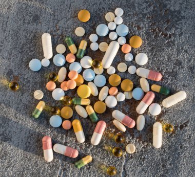 Gri doku arka planında farklı renkli ilaçlar ve haplar. Sağlık hizmetleri kavramı. Boşluğu kopyala.