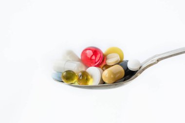 Beyaz arka planda bir kaşıkta çeşitli ilaç hapları, tabletler ve kapsüller. Sağlık sigortası konsepti. Boşluğu kopyala.