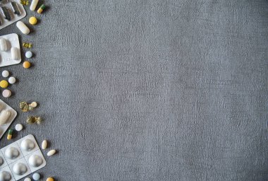 Gri doku arka planında farklı renkli ilaçlar ve haplar. Sağlık hizmetleri kavramı. Boşluğu kopyala.