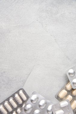 Gri doku arka planında farklı renkli ilaçlar ve haplar. Sağlık hizmetleri kavramı. Boşluğu kopyala.