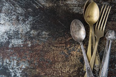 Klasik tarzda masa ayarı. Antika çatal, bıçak, kaşık, eskimiş arka plan. Metin için boşluk, düz uzanma