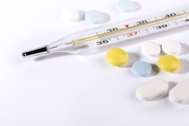 Beyaz arka planda haplar ve termometre. Grip salgını kavramı. Boşluğu kopyala.