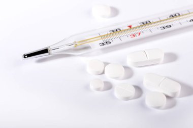 Beyaz arka planda haplar ve termometre. Grip salgını kavramı. Boşluğu kopyala.