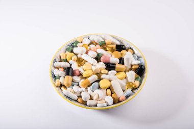 Beyaz tabakta haplar. Bıçak ve çatal jesti tabakta bulunan tabaktan hoşlanmadı. Tabakta çatal bıçakla yemek kılığına girmiş bir yığın renkli tablet. İlaçlar beyaz tabakta.