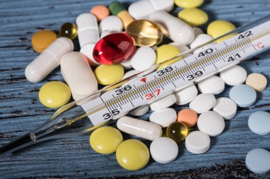 Mavi arka planda haplar ve termometre. Grip salgını kavramı. Boşluğu kopyala.