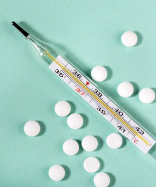 Beyaz arka planda haplar ve termometre. Grip salgını kavramı. Boşluğu kopyala.