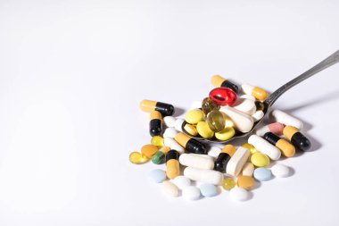 Beyaz arka planda bir kaşıkta çeşitli ilaç hapları, tabletler ve kapsüller. Sağlık sigortası konsepti. Boşluğu kopyala.