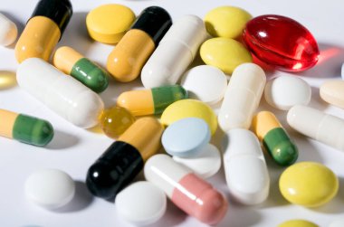 İlaçlar ve haplar beyaz tabakta. Tabakta yemek kılığına girmiş, beyaz tabakta çatal bıçak takımı olan çok renkli tabletler. Beyaz arkaplanda izole.