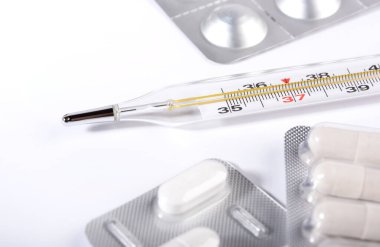 Beyaz arka planda haplar ve termometre. Grip salgını kavramı. Boşluğu kopyala.