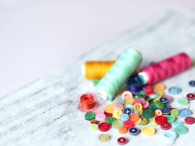 Dikiş işi için aksesuar ve aksesuar dikiyorum. İplik makaraları, raptiyeler, düğmeler, beyaz tahta arka plandaki kurdeleler. Kopyala lütfen. Dikiş, nakış, zanaat, dikiş kursları, eğitim..