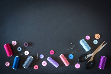 Dikiş işi için aksesuar ve aksesuar dikiyorum. İplik makaraları, raptiyeler, düğmeler, kara tahta arka planındaki kurdeleler. Kopyala lütfen. Dikiş, nakış, zanaat, dikiş kursları, eğitim..