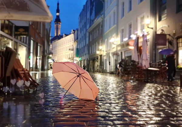タリン旧市街光ピンク色の傘雨季通りの夜の光が都市の人々がヨーロッパでストリートカフェ休日旅行を歩くエストニアの都市パノラマ秋の夏の季節 — ストック写真