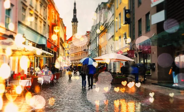  Sonbahar yaprakları yağmurlu bir akşam, yağmurlu bir hava, yapraklar dökülüyor şemsiye altında yürüyen insanlar Estonya 'nın Tallinn şehrinde eski bir tatil gününde bulanık bir ışık. 