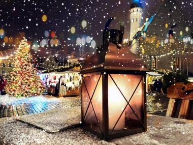 Christmas night decoration and red candle red glass cup on market place kiosk top in Tallinn old town city night blurred light people walking on street ,medieval house in the city ,holiday in  Europe 