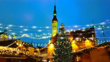 night  Christmas  tree from restaurant window view on Old town hall square holiday in Tallinn medieval street  city. tree  people walking under umbrellas on street  blurred evening light lamp life style  urban travel to Estonia in Europa 