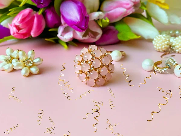 pink opal , gold  jewelry ,white pearl ,rings, women accessories  and earrings with tulip flowers  Bouquet , costume luxury fashion accessory with gold elements abstract concept