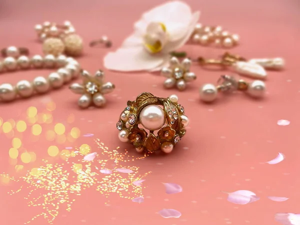white pearls Jewelry gold  Luxury Glamour fashion  costume jewelry  rings earrings bracelet with white orchid flowers petal  on pink and pink coral background women accessories  set collage