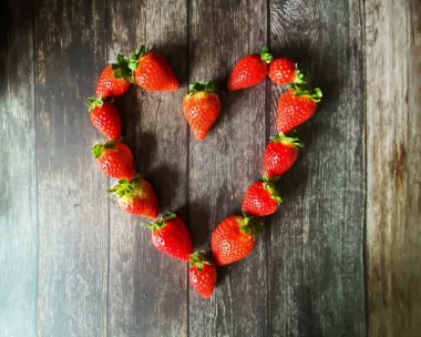 Çilek kırmızısı kalp şeklinde ahşap arka plan masa sepetinin üstünde.