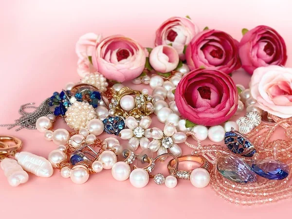 Jewelry background , gold  white pearl rings earrings bracelet  on pink   with blue gemstones  , red roses bouquet  women accessories fashion floral