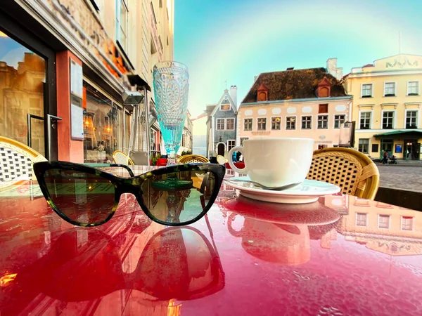 Tallinn,rainbow at sky ,cup of coffee on table top in street cafe ,blurred background ,Spring city  old town ,flowers bouquet ,blue sky,sunny spring day sunlight reflection holiday travel to Estonia