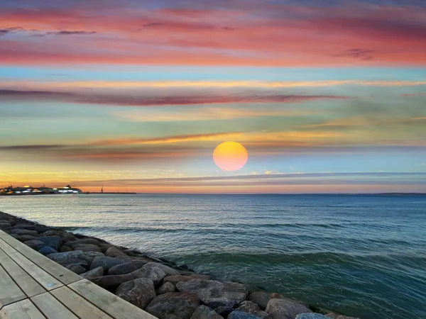 Sea sunset colorful evening sky and moon on cloudy  skyline,  light reflection on seawater, gold summer city  in   Tallinn old town panorama on beach  horizon ,nature background Estonia Baltic sea