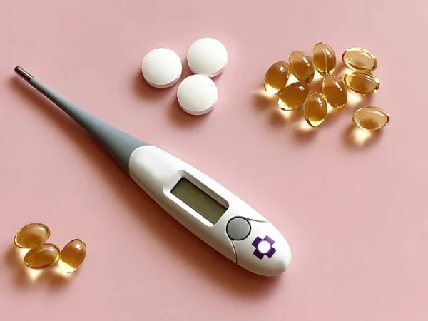 body medical  thermometer and vitamin on pink background